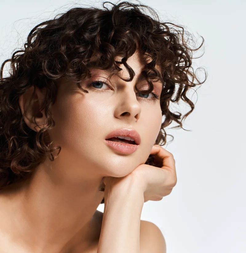 Frau mit Locken, die Hand am Kinn